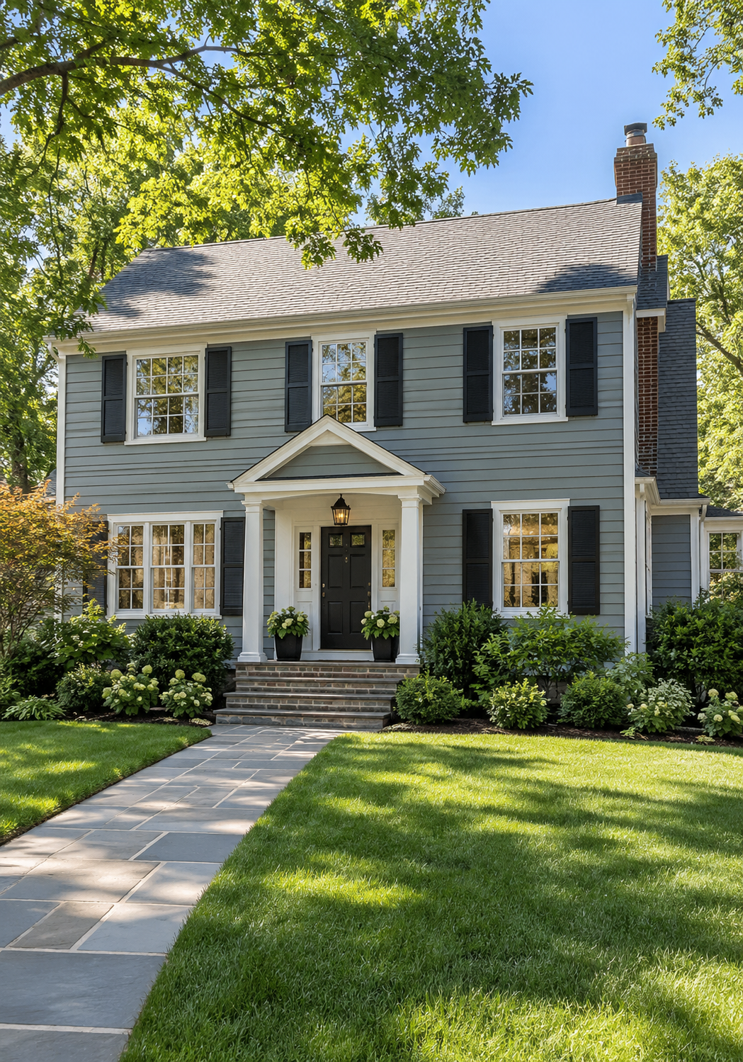 Two-story gray shingle Colonial-style home with black shutters, white trim, brick entry steps, and landscaped front yard representing mold inspection services in Wakefield, MA