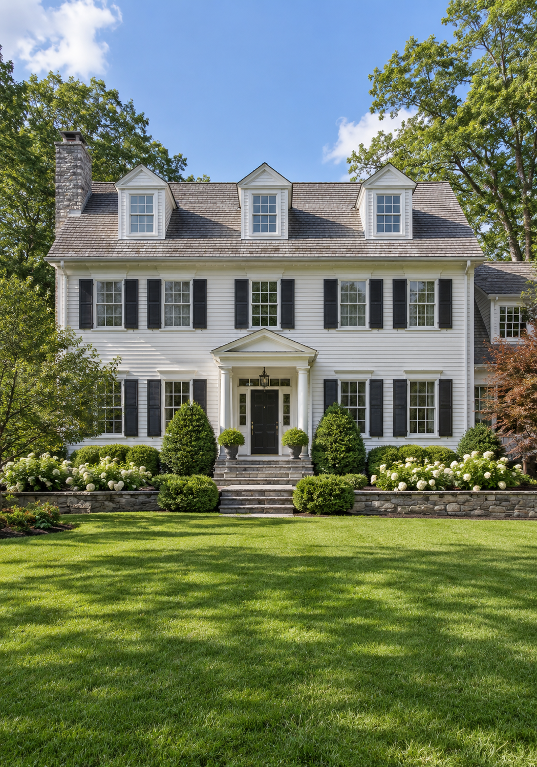 White Colonial-style home with black shutters, dormer windows, and stone chimney representing residential mold inspection services in North Andover, MA