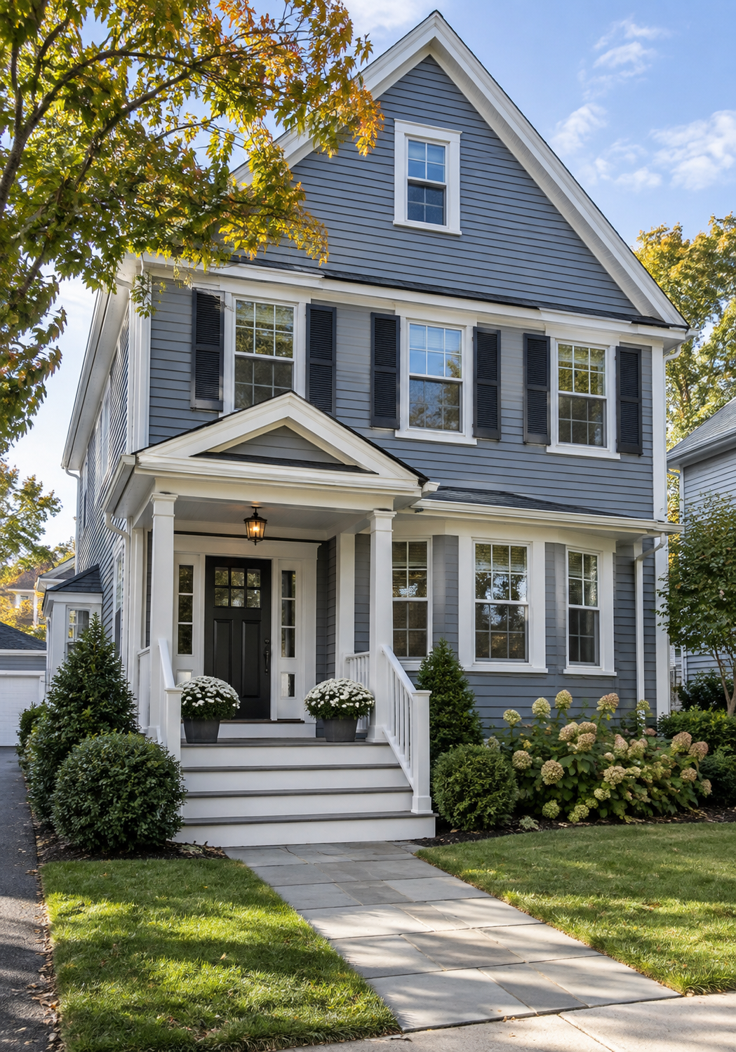 Two-story gray-blue Colonial-style home with black shutters, white trim, steep gabled roof, and covered front porch representing residential mold inspection services in Wakefield, MA